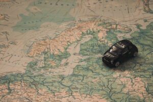 Ein kleines schwarzes Spielzeugauto steht auf einer Karte, die über der skandinavischen Region in Nordeuropa, einschließlich Norwegen, Schweden und Finnland, positioniert ist. Die Karte zeigt die umliegenden Länder und Gewässer.