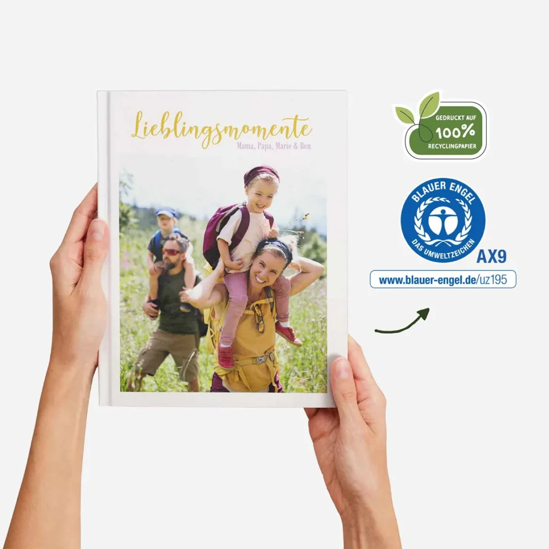 Person hält ein Fotobuch mit dem Titel „Lieblingsmomente“, das eine Familie beim Wandern in der Natur zeigt. Das Natur Pur Fotobuch von allcop ist auf der rechten Seite mit Umweltzeichen versehen, die auf 100 % Recyclingpapier und die Blauer Engel-Zertifizierung hinweisen.