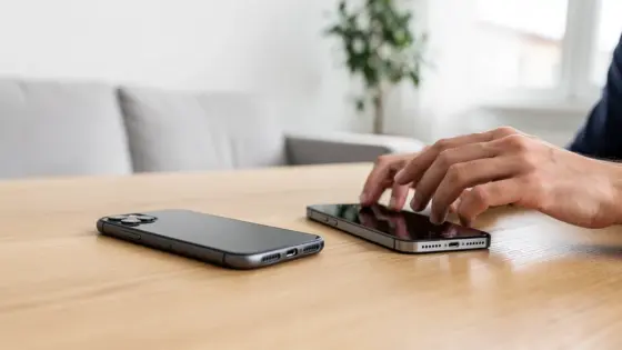 Hände wechseln an einem Holztisch von einem alten zu einem neuen Smartphone