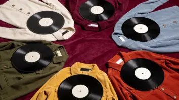 Sechs unterschiedliche Vintage-Kleidungsstücke liegen jeweils neben einer unbeschrifteten Schallplatte auf pflaumenfarbenem Stoff.
